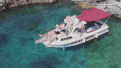 Boat anchored in a secluded beach on Cres island during the Natura Pura boat tour, with guests relaxing on the front sundeck